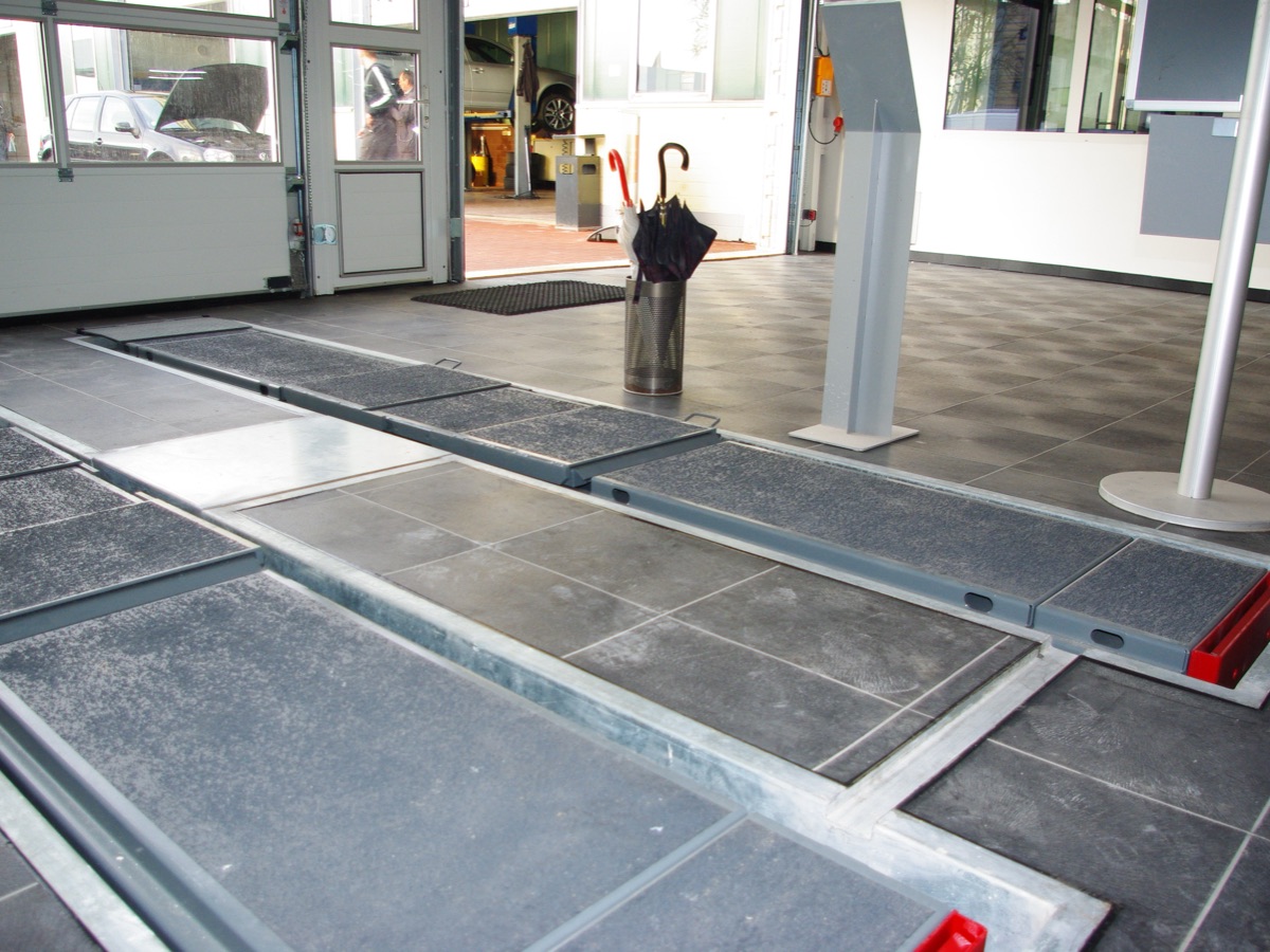 Werkstatthalle eines Autohauses mit Grubenabdeckung, der Boden wird gerade verlegt