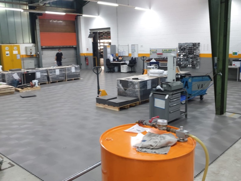 Maschinenhalle mit Paletten und orangefarbenem Fass auf dem neuen Boden